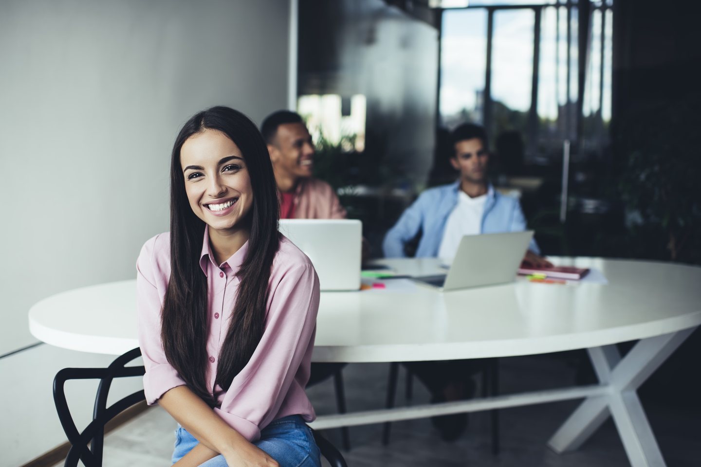 Anna, the marketer: a young woman smiling in an office, with two colleagues at laptops behind her